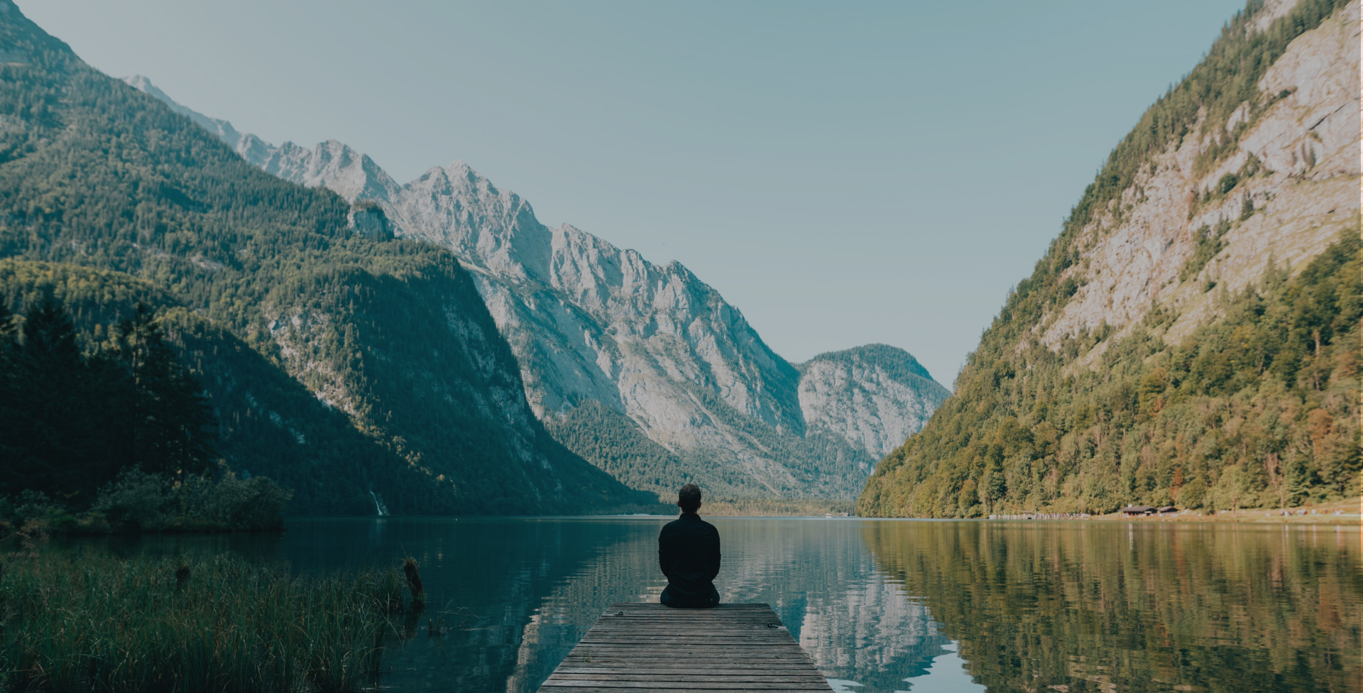 Man sitting at end of dock surrounded by nature