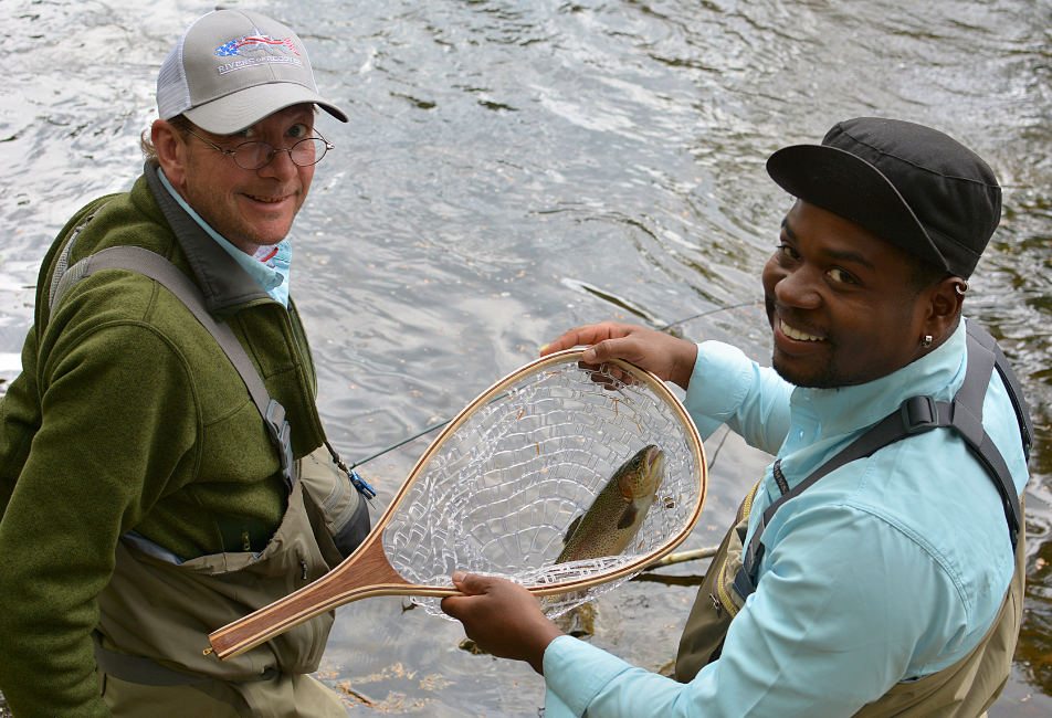 two men showing off a fish they caught in a net