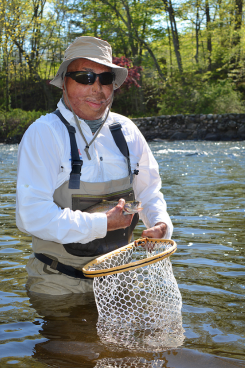 veteran Jose Jauregui standing in a river holding a fish he caught